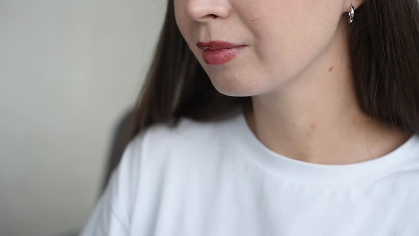 young beautiful caucasian brunette woman drinks apple juice in cafe or at home, smiling widely, casual clothes, white T-shirt, white cup
