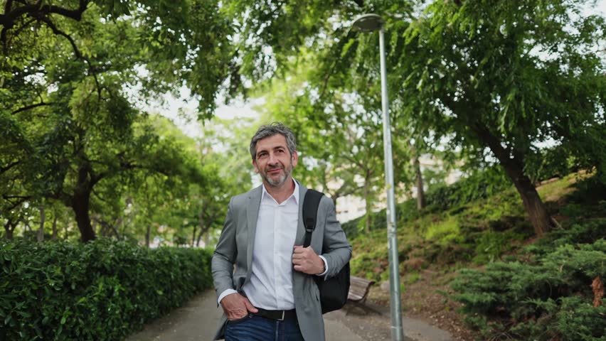 Businessman walking in park slow motion montage