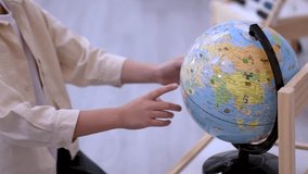 Adult guides young child exploring world globe in bright classroom, close-up hands, smooth camera movement - Powered by Shutterstock - Get 15% off with code: PIKWIZARD15
