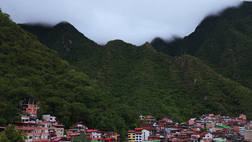 Aguas Calientes Machu Picchu town rainy season cloudy afternoon Peru aerial drone Peruvian Andes Mountains Urabumba river jungle lower highlands Inca trail citadel landscape buildings circle right