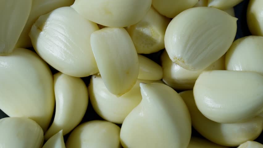 Rotating pile of peeled garlic cloves in top view