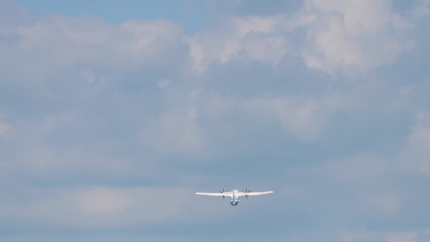Footage of airplane gaining altitude in blue cloudy sky, rear view. Long shot of airliner flying away