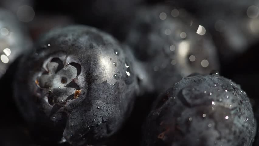Macro shot of a person picking a plump blueberry from a basket, highlighting fresh fruit, healthy eating, and close-up food detail.