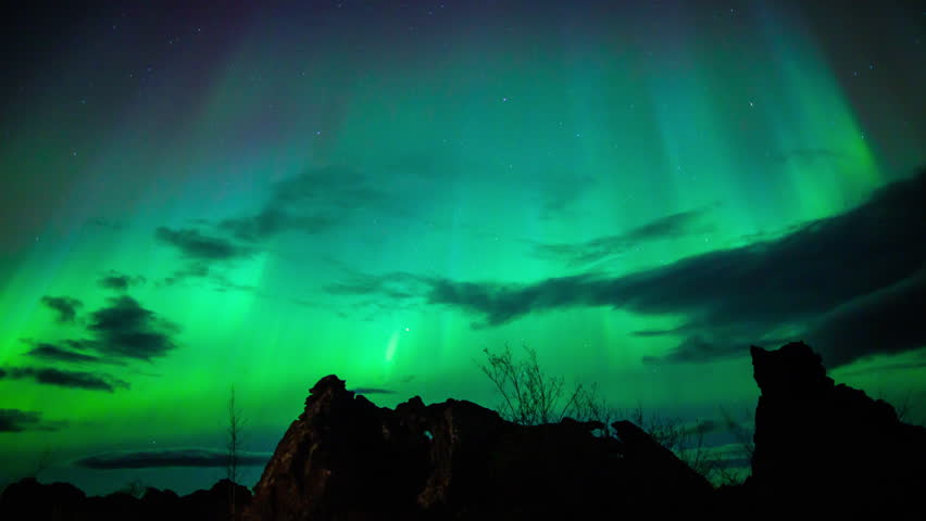 Aurora borealis glowing green blue columns with cloud over lava field, in north east Iceland. Time lapse.