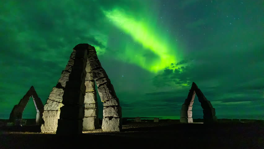 Aurora borealis glowing green columns over the iconic landmark Arctic Henge, in north east Iceland. Smooth time lapse copy space.