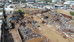 Ascending top-down drone view of scrapyard recycling facility with orange excavators, metal piles, and industrial structures - Powered by Shutterstock - Get 15% off with code: PIKWIZARD15