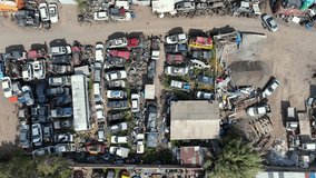 Panning top-down drone view of junkyard with rows of scrapped cars organized in patterns, auto salvage yard with metal piles - Powered by Shutterstock - Get 15% off with code: PIKWIZARD15