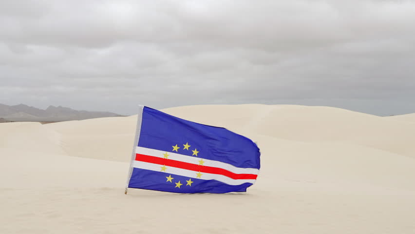 The Cape Verde flag flies in the Viana Desert at overcast day, Boa Vista island, Cape Verde.