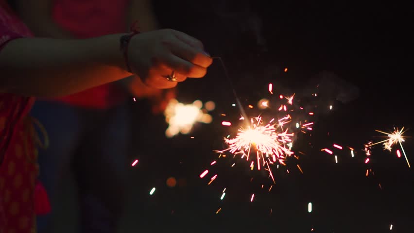 People holding sparkler and celebrating new year's eve. Girl having fun during Christmas holidays. Children enjoying firecrackers. Copy space in black background.