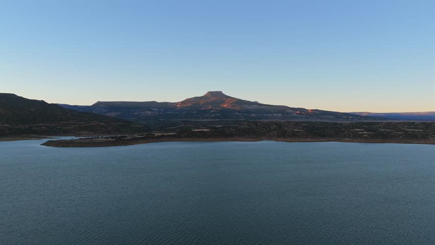 Wide aerial shot revealing the famous Cerro Pedernal mesa and the water of Abiquiu Lake. This classic New Mexico landscape was a primary subject for the iconic artist Georgia Okeeffe.