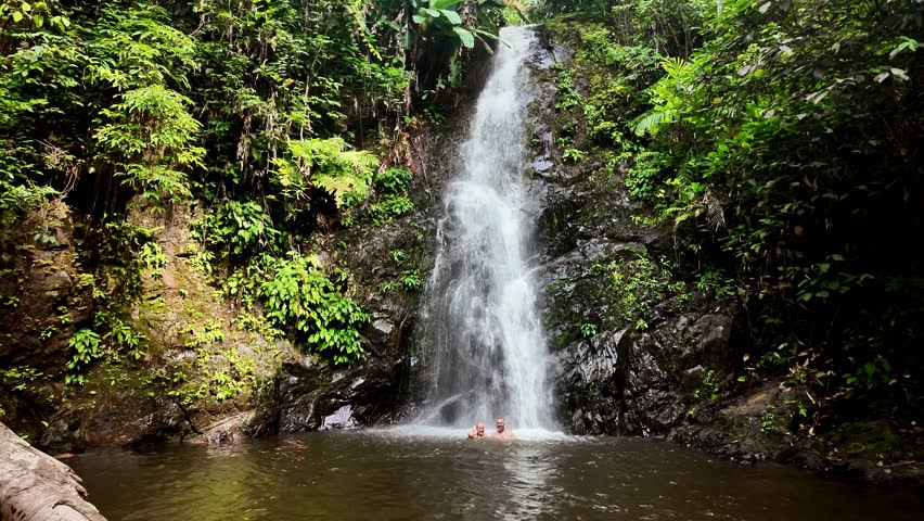 A couple in love swims under a waterfall in the jungle. A waterfall called Durian. Langkawi Island. Malaysia