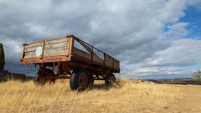 Timelapse shows an old tractor trailer and speed limit sign from a low angle as dramatic clouds move overhead.