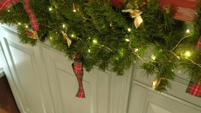 Closeup festive garland, golden bow, warm fairy lights on pine. Shimmering red ornament hanging against wooden wall. Cozy Christmas scene. Warm holiday ambiance. Glowing ornaments. Celebratory decor - Powered by Shutterstock - Get 15% off with code: PIKWIZARD15