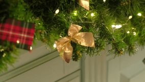 Closeup festive garland, golden bow, warm fairy lights on pine. Shimmering red ornament hanging against wooden wall. Cozy Christmas scene. Warm holiday ambiance. Glowing ornaments. Celebratory decor - Powered by Shutterstock - Get 15% off with code: PIKWIZARD15