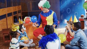 Clown showing blue balloon at kids party, causing gold confetti bursting around kids engaging crowd. Entertainer, costume, colorful, children, celebration, decor, backdrop - Powered by Shutterstock - Get 15% off with code: PIKWIZARD15