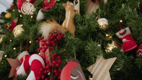 Close-up of Christmas tree with festive ornaments, golden baubles, red ribbons, decorative squirrel, and twinkling lights shining through green branches in modern shopping mall setting - Powered by Shutterstock - Get 15% off with code: PIKWIZARD15
