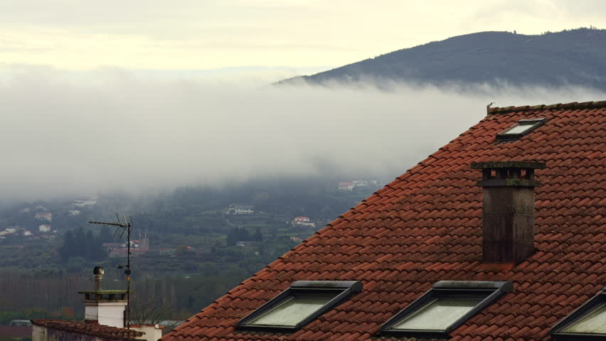 Fog Rolling Over Hills Behind Tiled Rooftop