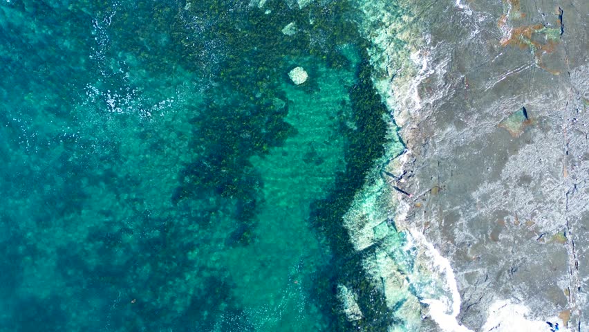 Drone aerial landscape of waves breaking along seaweed sandbar reef in ocean bay inlet on beach coastline and rocky headland of Gerroa Gerringong South Coast Australia travel tourism fishing surfing