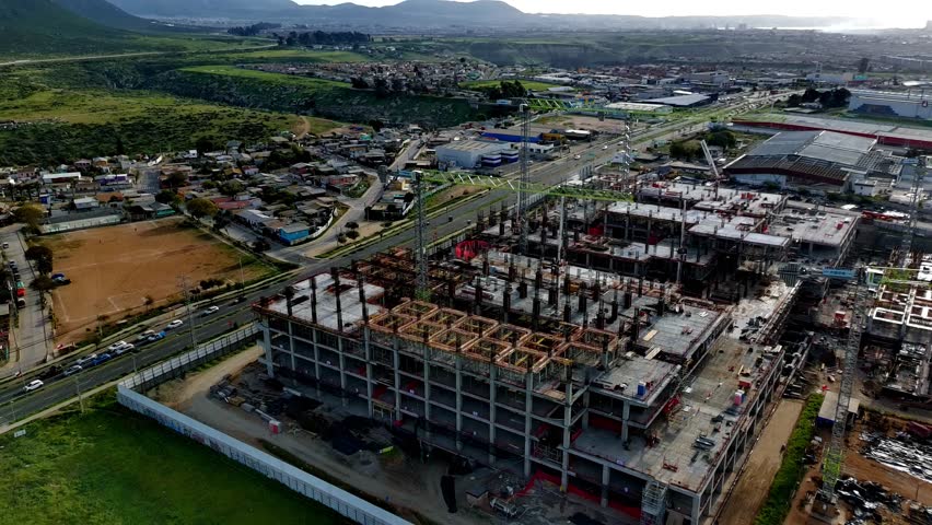 Aerial drone view of a large hospital construction site with cranes and concrete structure in progress