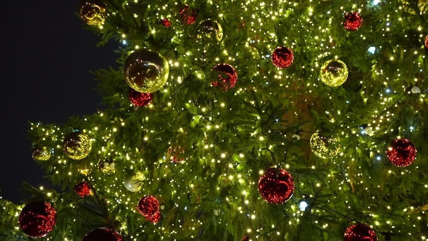 Close up of a light up christmas tree with ornaments at night