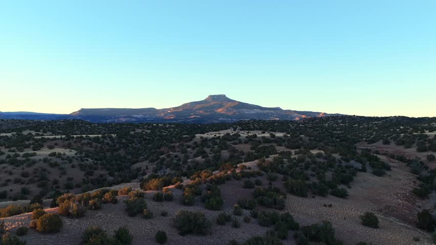 A dramatic, vertical rise reveals the immense scale of Cerro Pedernal and Abiquiu Lake. This high desert panorama in New Mexico is the iconic terrain painted by Georgia O