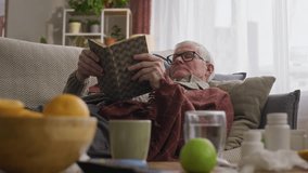 Handheld shot of drowsy elderly Caucasian man with cold taking nap while resting on sofa with book at home - Powered by Shutterstock - Get 15% off with code: PIKWIZARD15