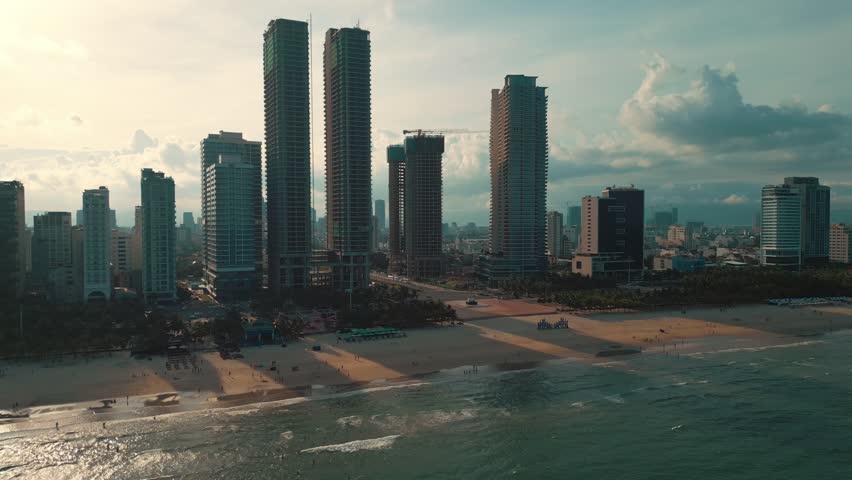 sunny sunset in Vietnamese coastal Da Nang city, My Khe sand beach and touristic My An and Son Tra district with modern skyscraper hotels and resorts, blue sea of Danang, Vietnam, aerial drone view 4k
