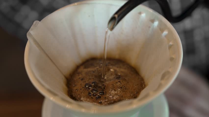 Freshly ground coffee blooms as water is poured in a slow controlled stream.