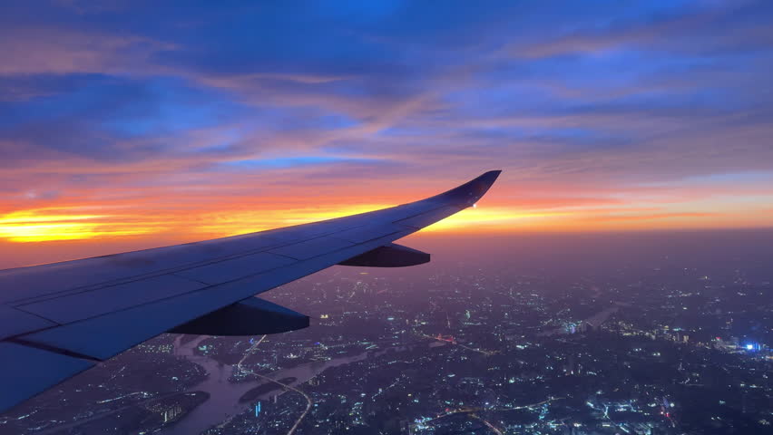 A View out of an airplane window onto city at sunset.