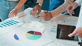 Hands of colleagues leaning over table. Team reviewing printed charts and diagrams. Markers and tablet on surface. Group analyzing workflow steps in office room. Data sheets guiding discussion. - Powered by Shutterstock - Get 15% off with code: PIKWIZARD15