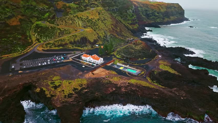 Aerial view of Ponta da Ferraria hot springs and the dramatic Atlantic Ocean coast on Sao Miguel Island, Azores, Portugal, showing volcanic cliffs and a striking coastal landscape.