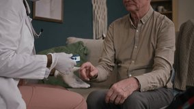 Cropped shot of healthcare worker in white coat applying pulse oximeter on finger of aged male patient while monitoring oxygen level at home - Powered by Shutterstock - Get 15% off with code: PIKWIZARD15