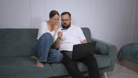 Joyful couple lounging on comfortable home sofa, sharing laptop and using credit card while enjoying seamless online shopping experience together - Powered by Shutterstock - Get 15% off with code: PIKWIZARD15