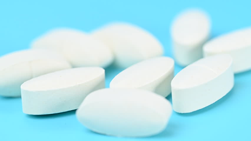 Video of white pills on a blue background