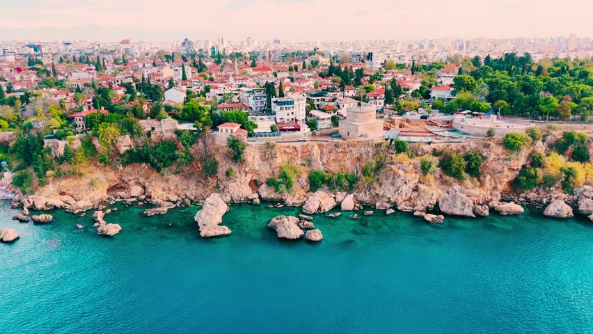 A breathtaking aerial view of Kaleiçi Old Town in Antalya, Turkey, featuring the Mediterranean Sea, Hıdırlık Tower, historic walls, and charming terracotta rooftops.