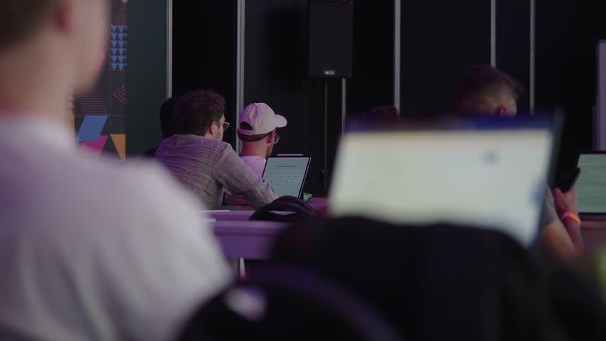 Footage of audience members attending talks at a tech event, listening, taking notes, and watching presentations. Ideal for conference promos and educational or business video projects.