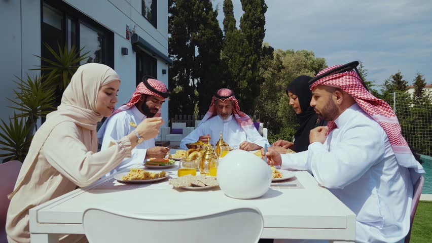 Muslim family celebrating eid al-fitr outdoors, sharing traditional dishes at a modern backyard dining table beside a swimming pool, multi-generational joy and togetherness