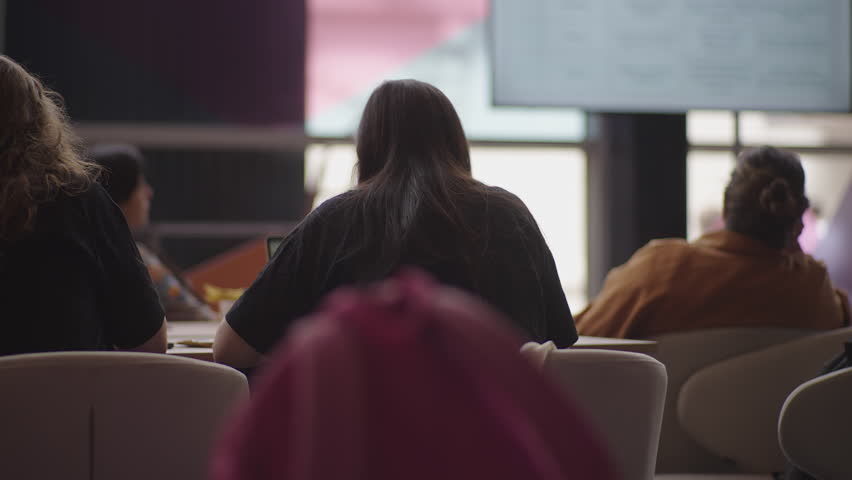 Footage of audience members attending talks at a tech event, listening, taking notes, and watching presentations. Ideal for conference promos and educational or business video projects.