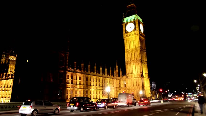 Illumination of Big Ben showcases iconic architecture surrounded by moving cars under night sky. Historic clock tower stands tall, capturing vibrant London atmosphere.