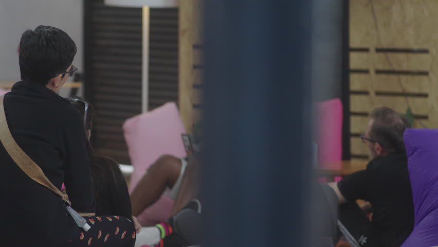 Footage of audience members attending talks at a tech event, listening, taking notes, and watching presentations. Ideal for conference promos and educational or business video projects.