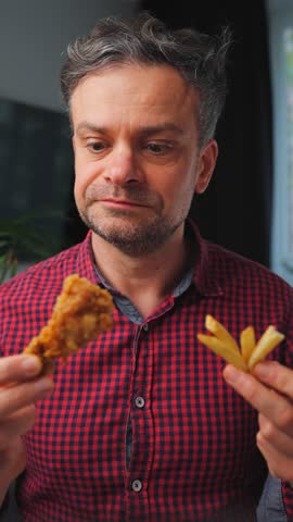 Junk food advertisement concept. Man eating fried chicken, enjoying fast food.