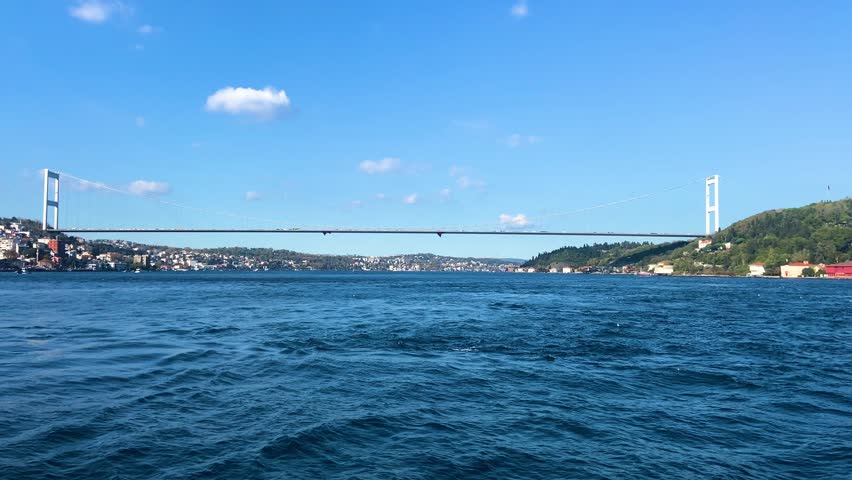 Cinematic view of Fatih Sultan Mehmet Bridge (Bosphorus Bridge) seen from a moving ferry boat in Istanbul, Turkey.