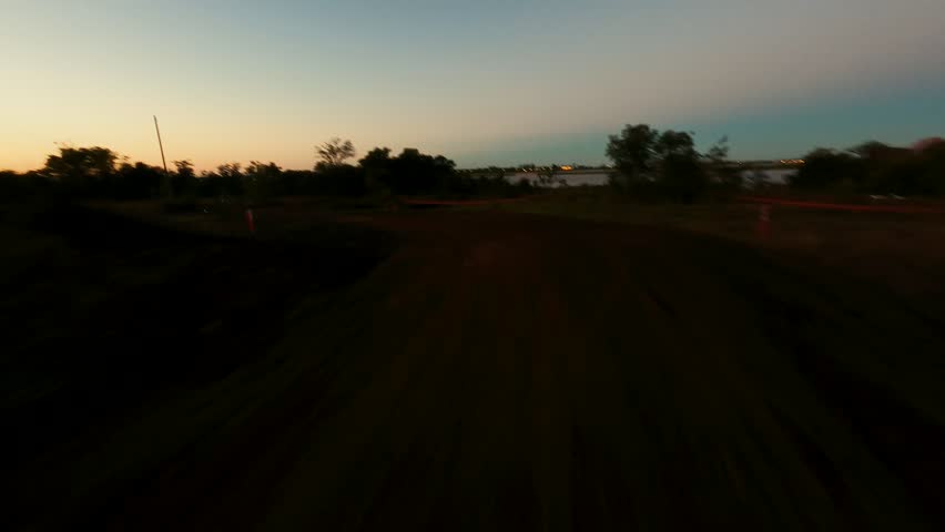 Tilted aerial shot over lakes at dusk, revealing contrasts between deep shadows and warm horizon light as the landscape transitions into night.