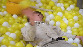 Teenager playing in ball pit with yellow and white balls - Powered by Shutterstock - Get 15% off with code: PIKWIZARD15