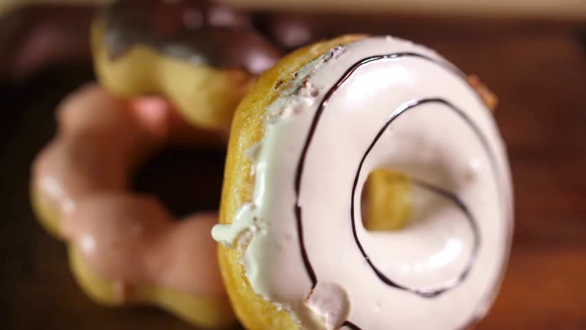 Variety of donuts sits close on wood, highlighting sweet icing and textures. Baked treats look fresh, glazed and ready to be eaten. food background