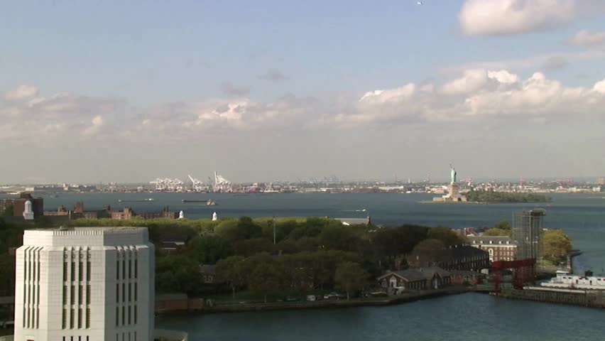 Vibrant skyline captures harbor scenery showcasing Statue of Liberty amid lively boats and clouds. Bright sunlight illuminates cityscape with lush green trees.