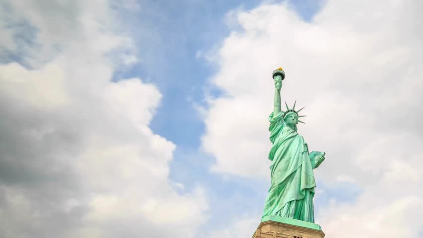 Statue of Liberty stands tall against blue skies, symbolizing freedom and hope in America. Visitors marvel at this monumental landmark, showcasing American architecture and history.