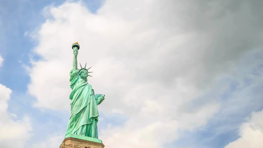 Iconic Statue of Liberty rises prominently in Manhattan skyline. Surrounded by dramatic clouds, this national monument symbolizes hope and freedom for visitors and citizens alike.