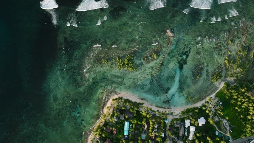 Aerial view of turquoise reef and pier stretch from the sandy coast into the sea. Siargao, Philippines. Cloud 9 Surfing Area.