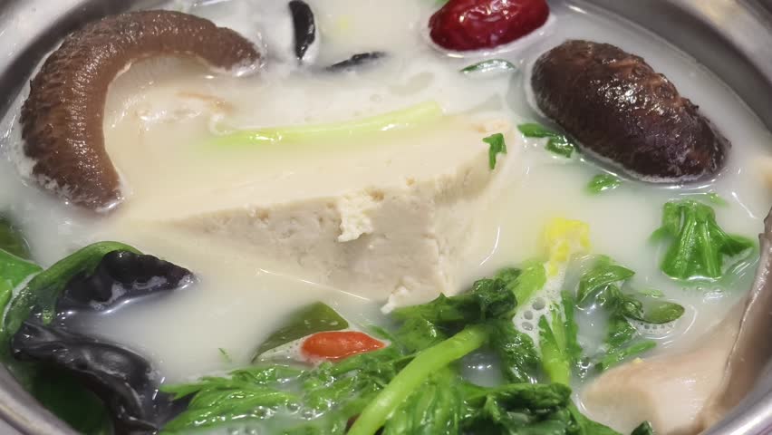 Closeup of boiling hotpot with mushroom, vegetable, beancurd in the soup.